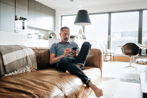 handsome bearded mid aged man looking at mobile on sofa